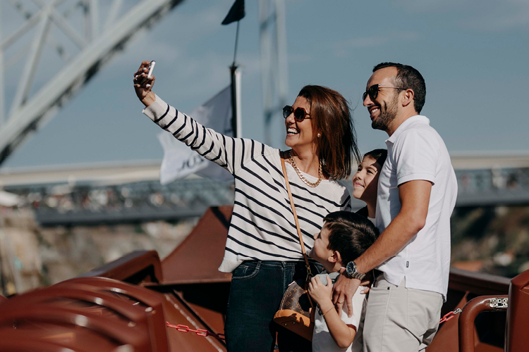 Happy family taking a picture on a Rabelo Boat during a Douro River bridge cruise
